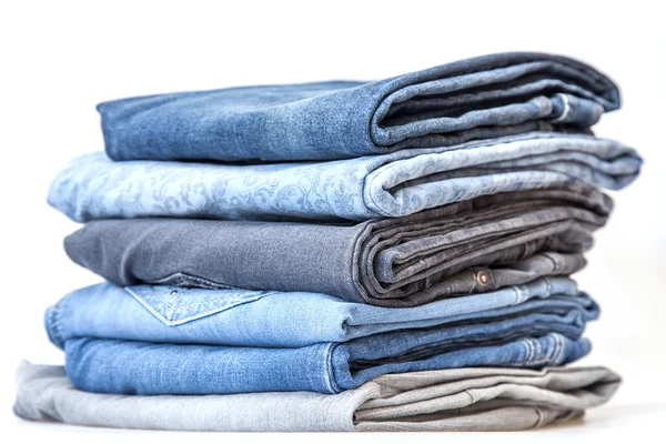 Pile of jeans of various colors on a counter in shop — Stock Photo, Image