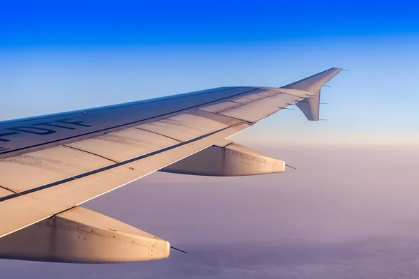 Flug bei Sonnenaufgang. Der Flügel des Flugzeugs und der Himmel leuchteten mit den Strahlen einer aufgehenden Sonne. Blick aus dem Fenster auf das Flugzeug — Stockfoto