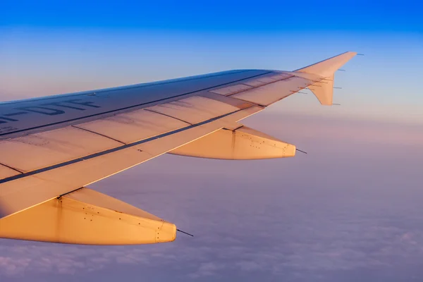 Flug bei Sonnenaufgang. Der Flügel des Flugzeugs und der Himmel leuchteten mit den Strahlen einer aufgehenden Sonne. Blick aus dem Fenster auf das Flugzeug — Stockfoto