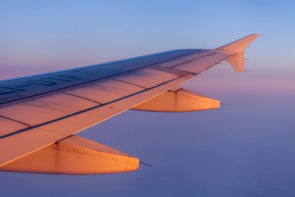 Lot o wschodzie słońca. Skrzydło samolotu i niebo oświetlone promieniami wschodzącego słońca. Widok samolotu z okna — Zdjęcie stockowe