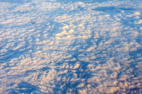 The top view on the sky and clouds from a window of the flying plane