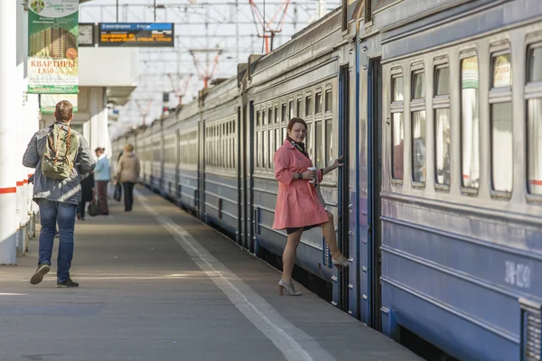 Pushkino, Russie, le 12 avril 2015. La femme en imperméable lumineux entre dans la voiture d'un train électrique régional — Photo