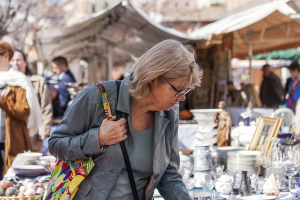 Nice, Francia, il 9 marzo 2015. Gli acquirenti considerano merci d'epoca su un banco di un mercato delle pulci su Cours Saleya Square. Il mercato Marche Du Cours Saleya - uno dei luoghi più conosciuti di Nizza — Foto Stock