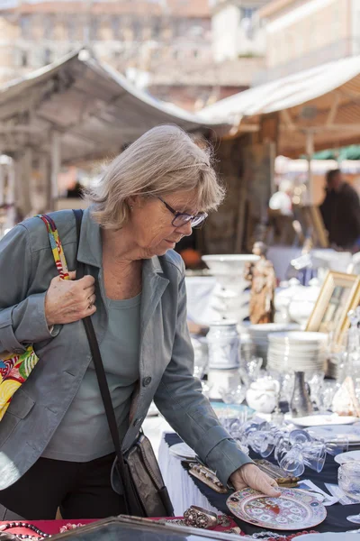 Nice, France, on March 9, 2015. Buyers consider vintage goods on a counter of a flea market on Cours Saleya Square. The Marche Du Cours Saleya market - one of the most known sights of Nice — Stock Photo, Image