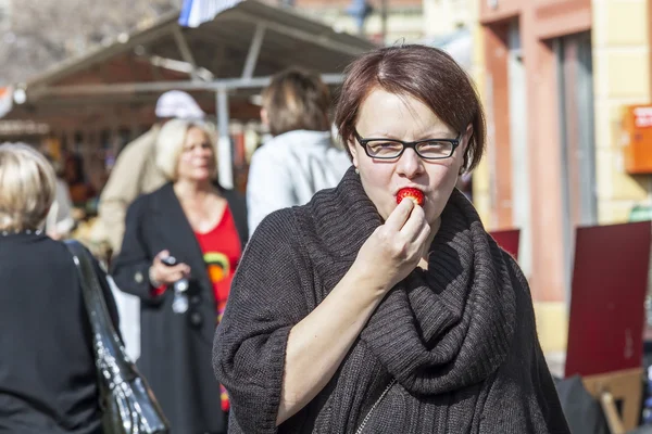 Nice, France, on March 11, 2015. The woman in the market tastes fresh strawberry — Stock Photo, Image