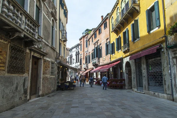 VENECIA, ITALIA - 29 DE ABRIL DE 2015. Los peatones van en la estrecha curva de la vieja calle — Foto de Stock