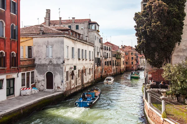 VENICE, ITALY - on April 29, 2015. Лодки различного назначения плавают на типичном уличном канале. Лодка является основным транспортным средством в островной части города — стоковое фото