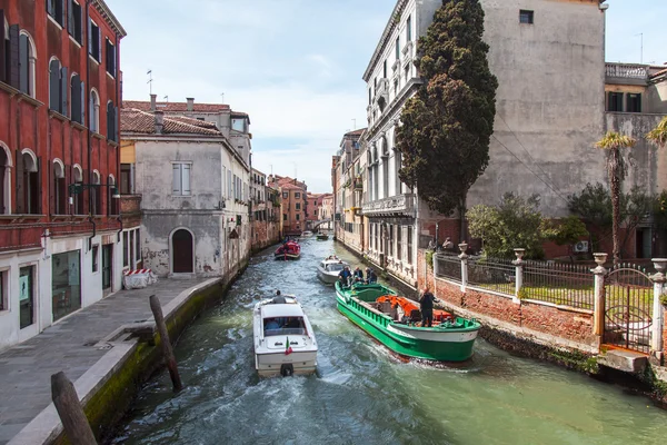 Venice, Italië - op 29 April 2015. Boten van verschillende functie drijven op de typische straat gracht. De boot is het belangrijkste voertuig in eiland deel van de stad — Stockfoto