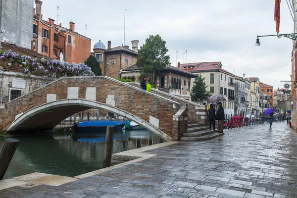 VENECIA, ITALIA - 29 DE ABRIL DE 2015. Una vista urbana típica en clima lluvioso. Canal de la calle y edificios antiguos en tierra —  Fotos de Stock