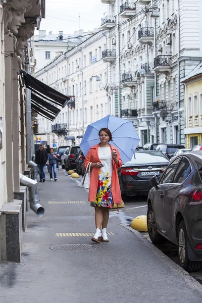 モスクワ、ロシア、2015 年 5 月 24 日に。明るいレインコートの女が雨の天気にポクロフカ通りに行く — ストック写真