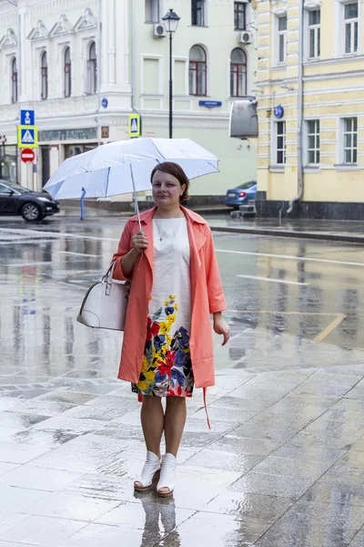 MOSCOW, RUSSIA, on MAY 24, 2015. The woman in a bright raincoat goes on Pokrovskaya Street to rainy weather — Stock Photo, Image