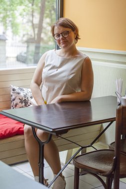 Kafede bir öğle yemeği için bekleyen küçük tablolar için kadın oturur