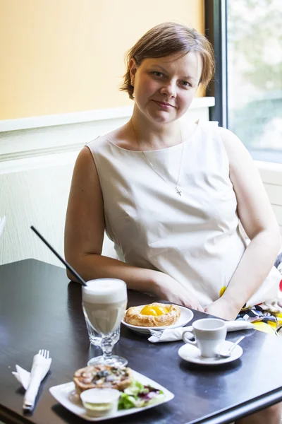 Kafede bir öğle yemeği için bekleyen küçük tablolar için kadın oturur