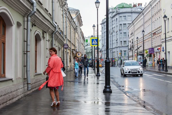 モスクワ、ロシア、2015 年 5 月 24 日に。明るいレインコートの女が雨の天気にポクロフカ通りに行く — ストック写真