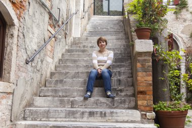 Venice, İtalya - 1 Mayıs 2015 tarihinde. Eski bir taş merdiven basamaklarında kadın oturur