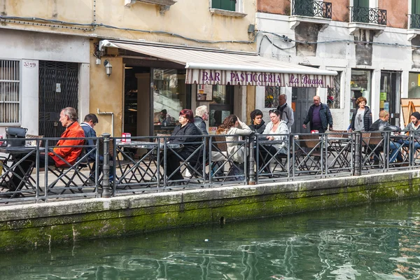 VENISE, ITALIE - le 1er mai 2015. Paysage typique de la ville. Les gens se reposent et mangent dans un café d'été sur la rive du canal — Photo