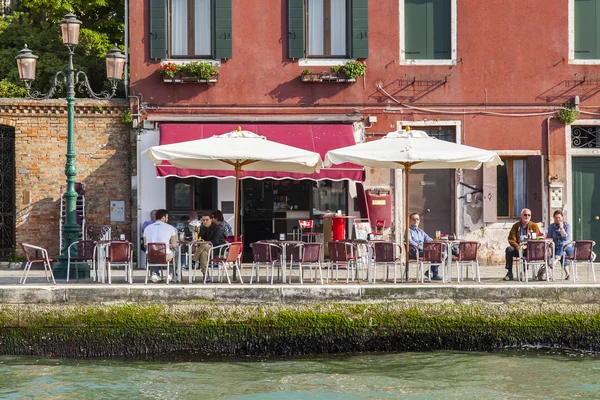 VENICE, ITALY - on APRIL 30, 2015. People have a rest and eat in summer cafe on the bank of the channel — Stock Photo, Image