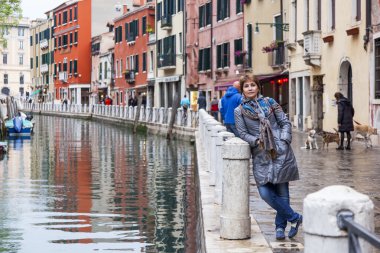 VENICE, ITALY - on MAY 1, 2015. Typical street canal in spring evening. Tourist has photo against the venetian landscape
