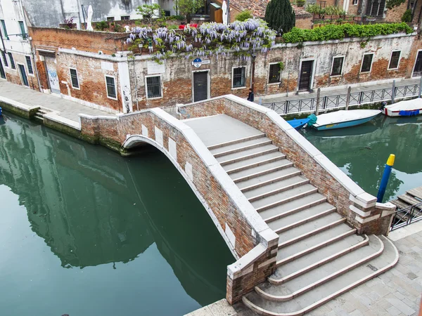 VENISE, ITALIE - le 3 mai 2015. Le pont avec marches à travers le canal de la rue, la vue de dessus d'une fenêtre de la maison sur la rive du canal — Photo