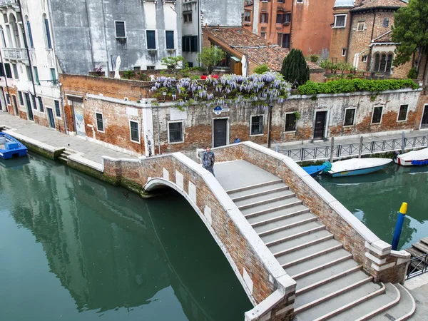 VENISE, ITALIE - le 3 mai 2015. Le pont avec marches à travers le canal de la rue, la vue de dessus d'une fenêtre de la maison sur la rive du canal — Photo