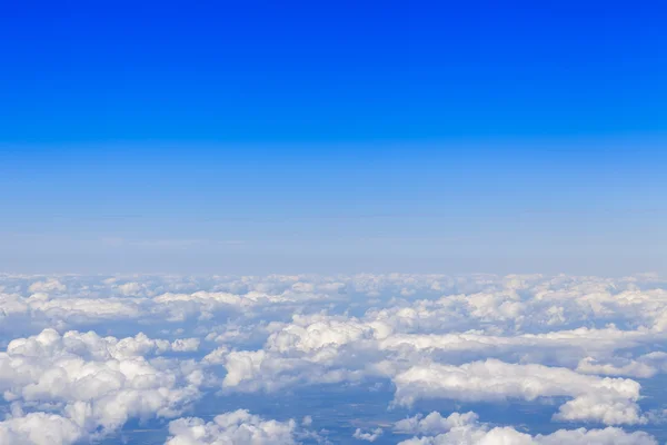 Utsikt från fönstret i flygande planet på moln nedan och den ljusa himlen — Stockfoto