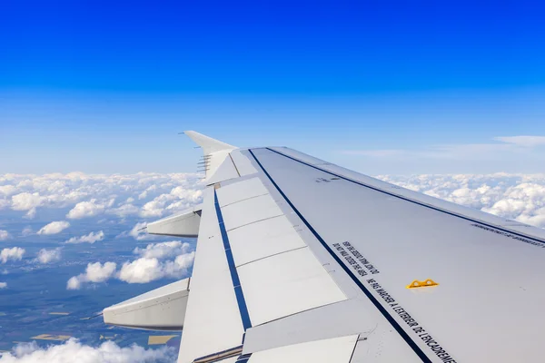 Blick aus dem Fenster des fliegenden Flugzeugs auf Wolken darunter und den strahlend blauen Himmel — Stockfoto