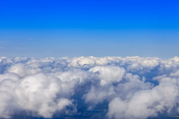 雲の下と明るい青空に飛ぶ飛行機の窓からの眺め — ストック写真