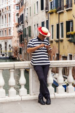 VENICE, ITALY - on MAY 3, 2015. The bridge via the channel. The gondolier holds the smartphone in hand