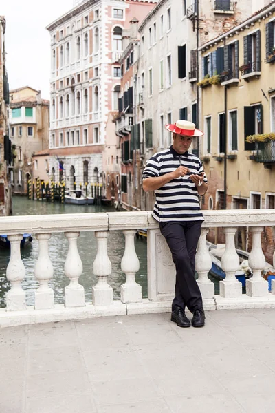 VENICE, ITÁLIA - em 3 de maio de 2015. A ponte através do canal. O gondoleiro segura o smartphone na mão — Fotografia de Stock