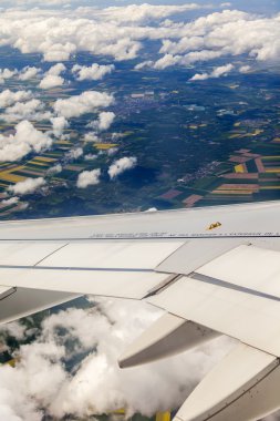 Bulutlar ve bir karasal yüzey üzerinde uçan uçağın penceresinden görüntülemek