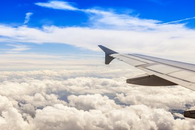 Bulutlar ve bir karasal yüzey üzerinde uçan uçağın penceresinden görüntülemek