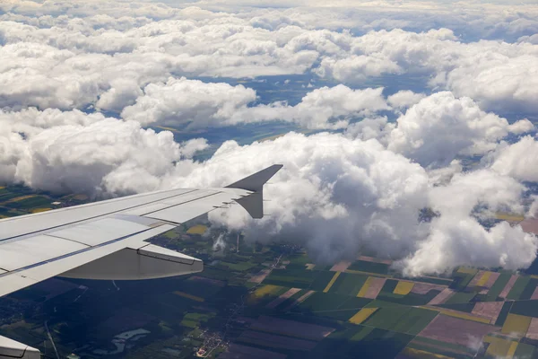 雲と地上の表面の下に飛ぶ飛行機の窓からの眺め — ストック写真