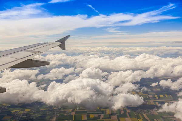 View from the window of the flying plane on clouds and a terrestrial surface below — Stock Photo, Image