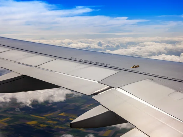 Widok z okna latający samolot na chmury i naziemnej poniżej powierzchni — Zdjęcie stockowe