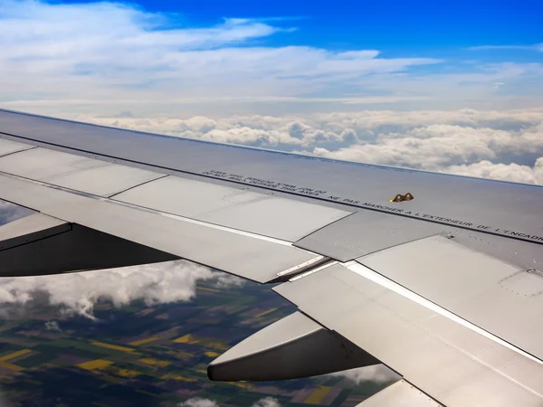 Vista dalla finestra dell'aereo volante su nuvole e una superficie terrestre sotto — Foto Stock