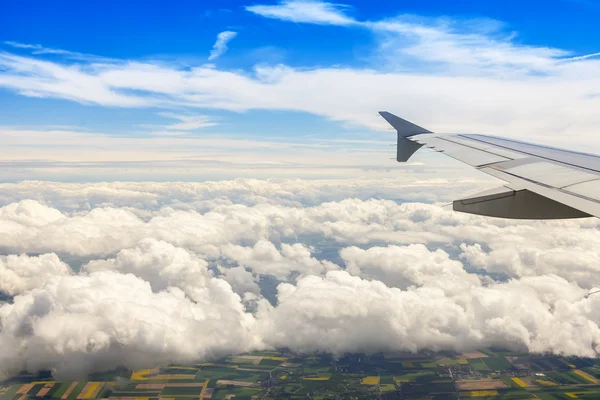 View from the window of the flying plane on clouds and a terrestrial surface below — Stock Photo, Image