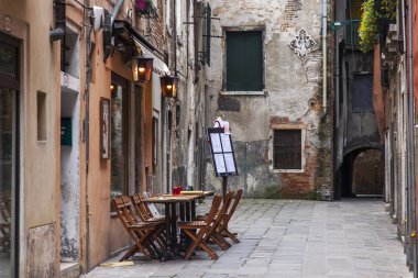 VENICE, ITALY on MAY 3, 2015. Typical city street. Old houses and small outside cafe, look in the cloudy spring morning