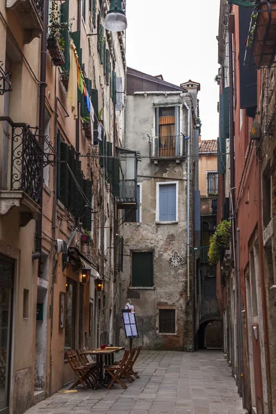 VENECIA, ITALIA en Mayo 3, 2015. Calle típica de la ciudad. Casas viejas y pequeño café al aire libre, mirar en la mañana nublada primavera — Foto de Stock