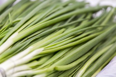 Bunches of green onions on a market counter clipart