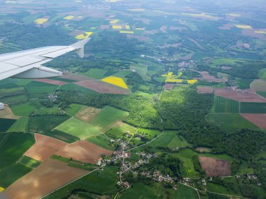 Bulutlar ve bir karasal yüzey üzerinde uçan uçağın penceresinden görüntülemek