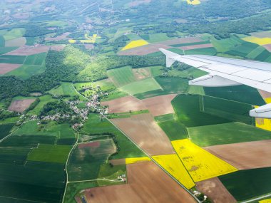 Bulutlar ve bir karasal yüzey üzerinde uçan uçağın penceresinden görüntülemek