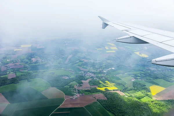 Bulutlar ve bir karasal yüzey üzerinde uçan uçağın penceresinden görüntülemek — Stok fotoğraf