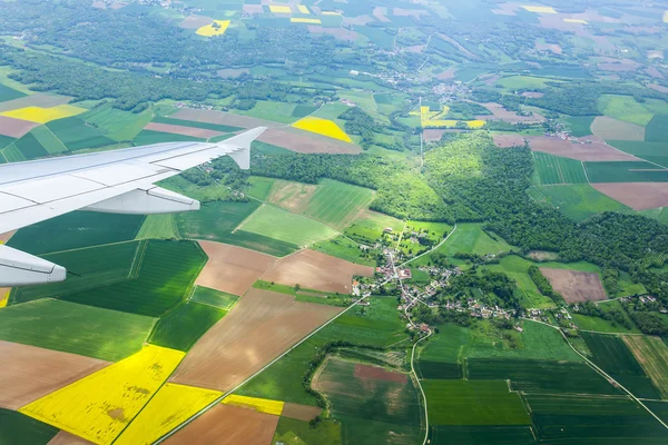 Vista desde la ventana del avión volador sobre las nubes y una superficie terrestre debajo — Foto de Stock