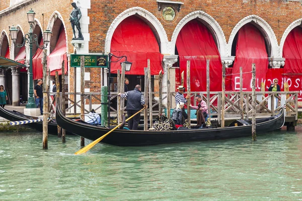 VENICE, ITALY - on MAY 4, 2015. Walk on a gondola on the Grand channel (Canal Grande) - one of the most known tourist attractions in Venice. Passengers take places in a gondola — Stock Photo, Image