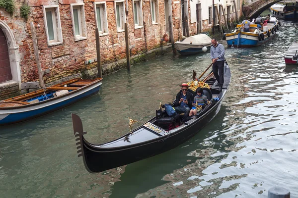 VENICE, ITALY - on MAY 4, 2015. The typical Venetian street canal and its reflection in water. The lonely gondola with passengers floats — Stock Photo, Image