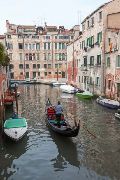 VENICE, ITALY - on MAY 4, 2015. The typical Venetian street canal and its reflection in water. The lonely gondola with passengers floats — Stock Photo, Image