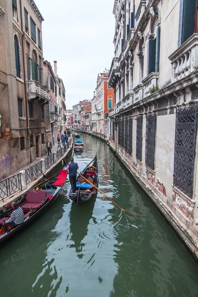 VENICE, ITALY - on MAY 2, 2015. The typical Venetian street canal and its reflection in water. The lonely gondola with passengers floats — Stock Photo, Image