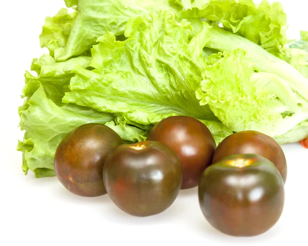 Folhas de salada fresca e tomates pretos — Fotografia de Stock