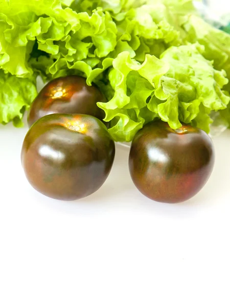 Blätter von frischem Salat und schwarzen Tomaten — Stockfoto