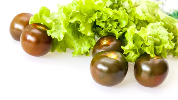 Folhas de salada fresca e tomates pretos — Fotografia de Stock